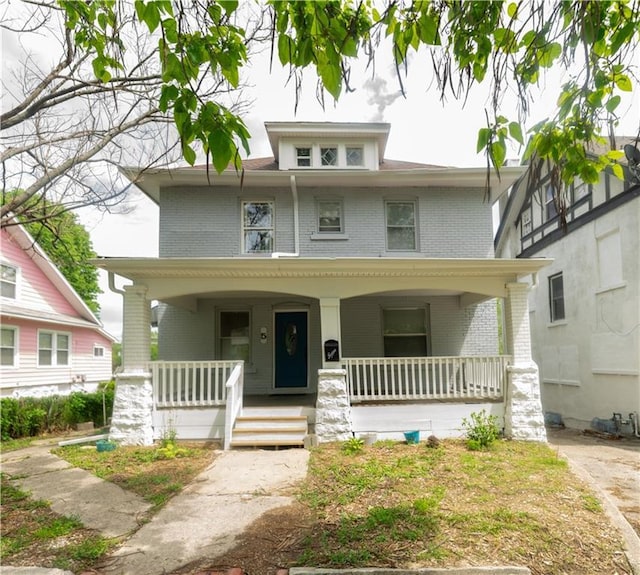 american foursquare style home with brick siding and covered porch