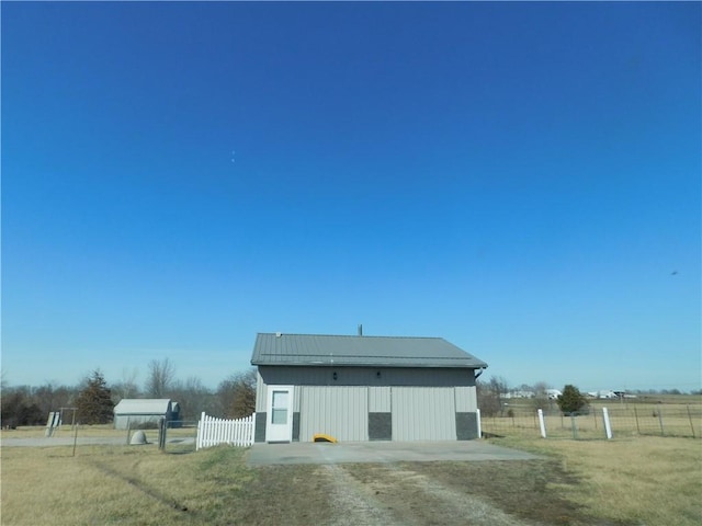 view of outdoor structure with a rural view, an outdoor structure, and fence