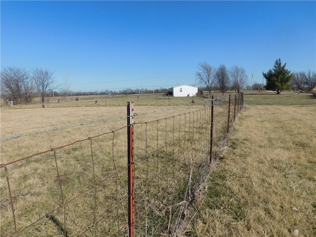 view of yard with a rural view, an outdoor structure, and fence