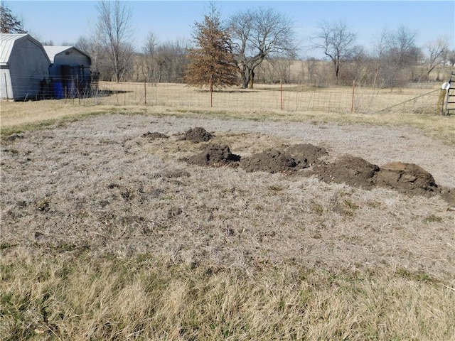 view of yard with a rural view, an outdoor structure, and fence