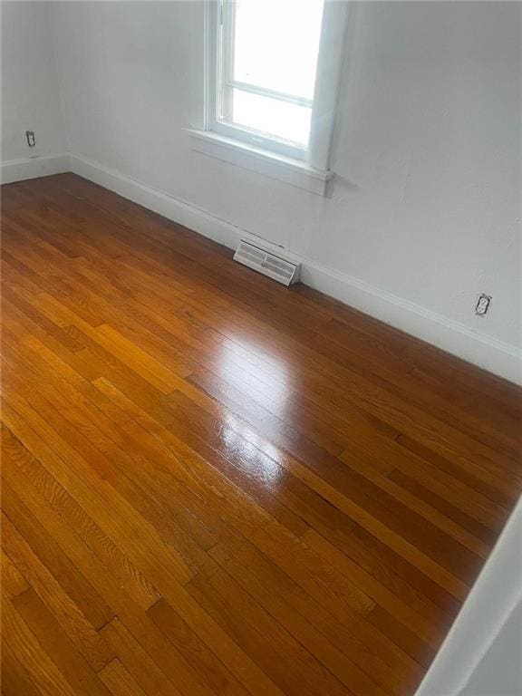 unfurnished room with hardwood / wood-style floors, baseboards, and visible vents