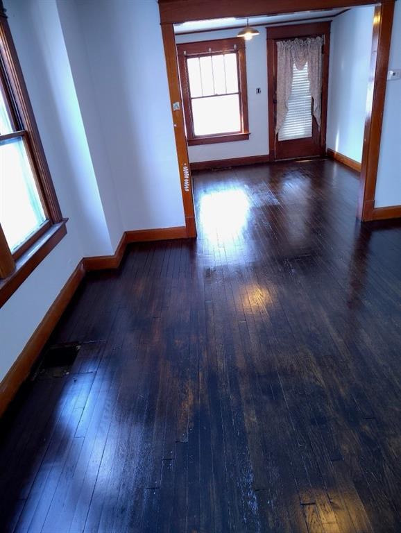 unfurnished room with baseboards and dark wood-style flooring