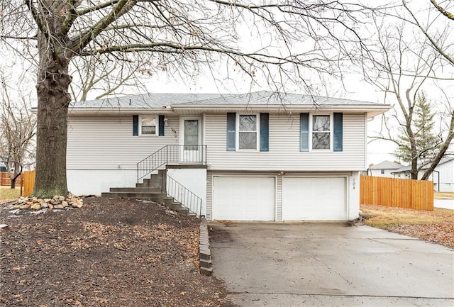 view of front of property featuring concrete driveway, a garage, and fence