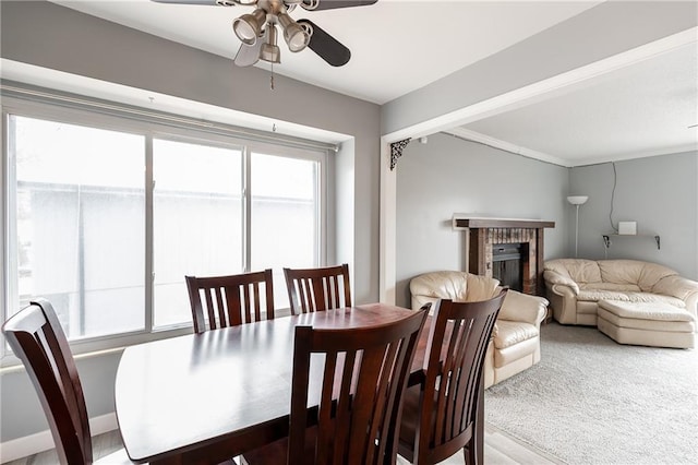 dining space with light carpet, ceiling fan, and a fireplace