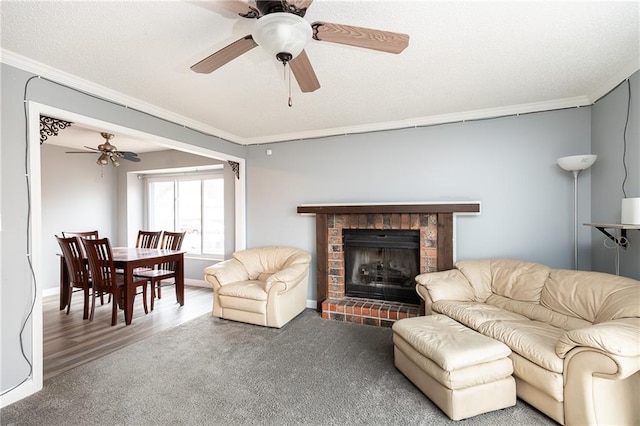 carpeted living room with a fireplace, crown molding, a ceiling fan, and a textured ceiling