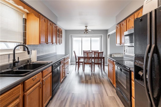 kitchen with dark countertops, decorative backsplash, black appliances, and a sink