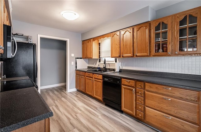 kitchen featuring black appliances, brown cabinetry, light wood-style floors, and a sink