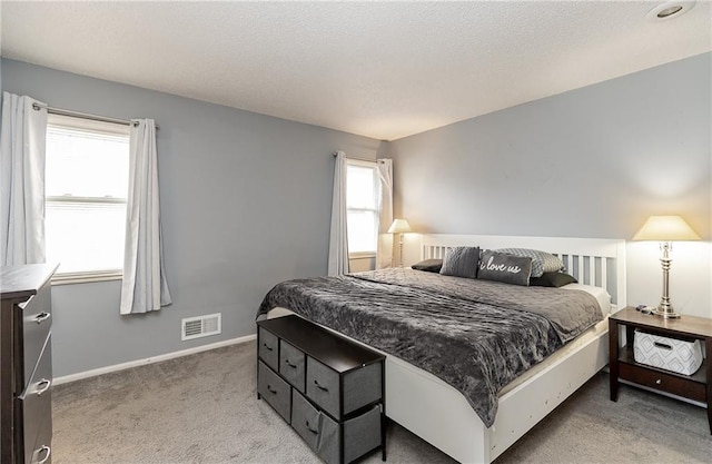 bedroom with visible vents, light carpet, a textured ceiling, and baseboards