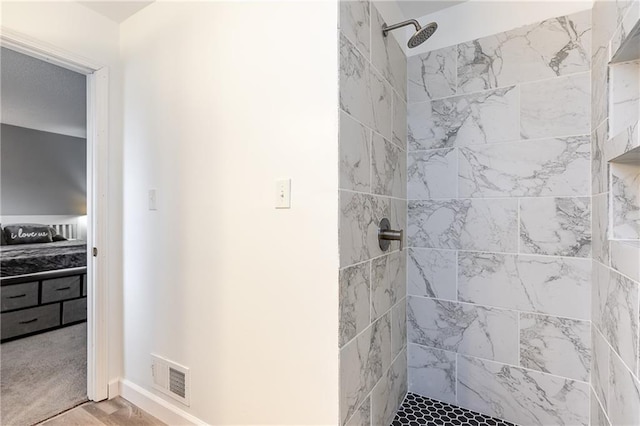 full bath featuring a tile shower, visible vents, and baseboards