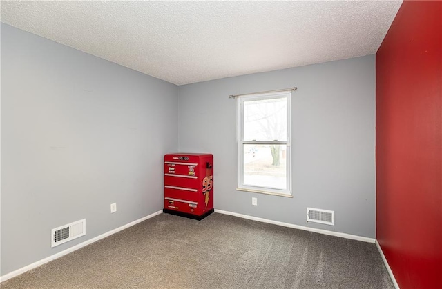 carpeted empty room featuring baseboards, visible vents, and a textured ceiling