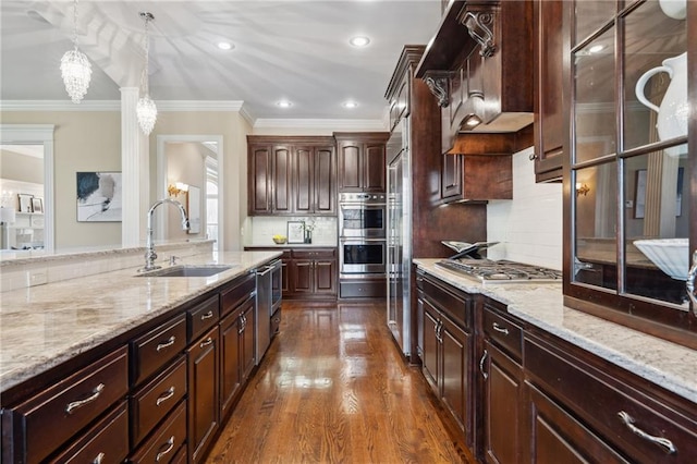 kitchen with a sink, crown molding, light stone countertops, pendant lighting, and dark wood-style flooring