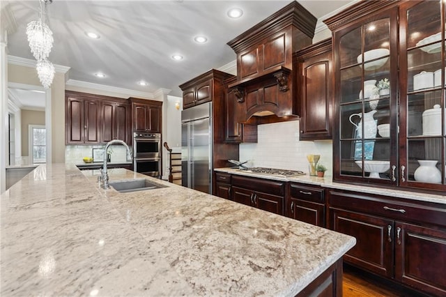 kitchen with pendant lighting, a sink, light stone counters, appliances with stainless steel finishes, and crown molding