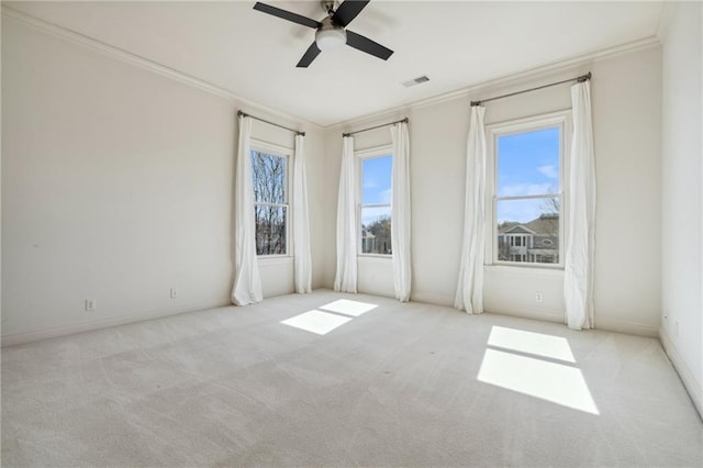 carpeted empty room featuring visible vents, plenty of natural light, and ornamental molding