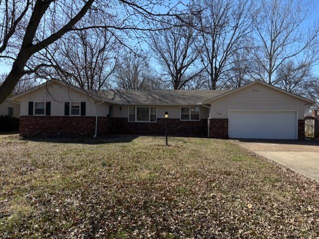 single story home with concrete driveway, an attached garage, and a front yard