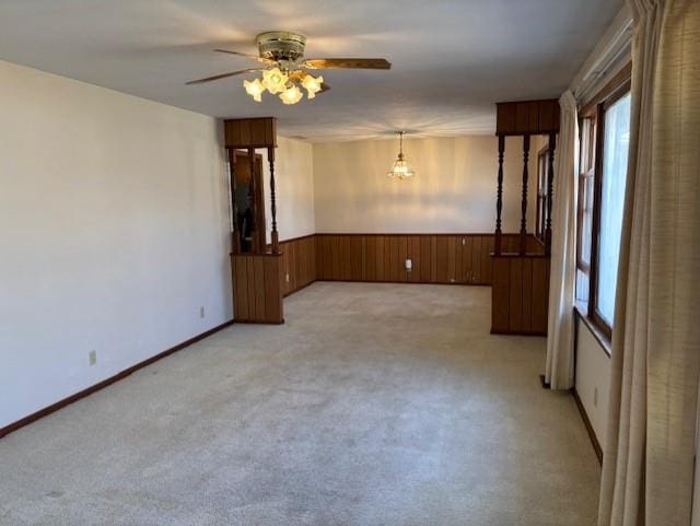 spare room with wooden walls, light colored carpet, a wainscoted wall, and ceiling fan