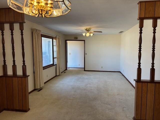 unfurnished room with visible vents, light colored carpet, ceiling fan with notable chandelier, and baseboards