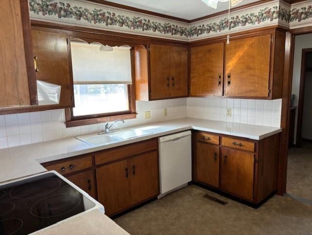 kitchen with brown cabinetry, a sink, light countertops, dishwasher, and backsplash