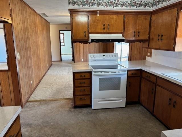 kitchen with white electric stove, under cabinet range hood, brown cabinetry, and light countertops