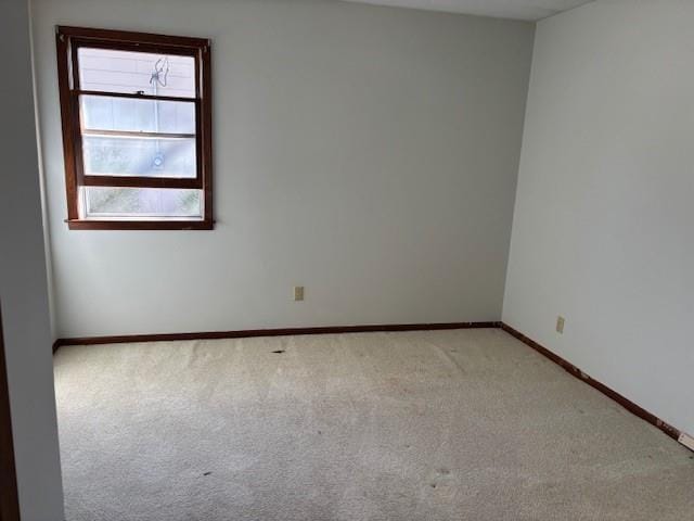 carpeted spare room featuring baseboards