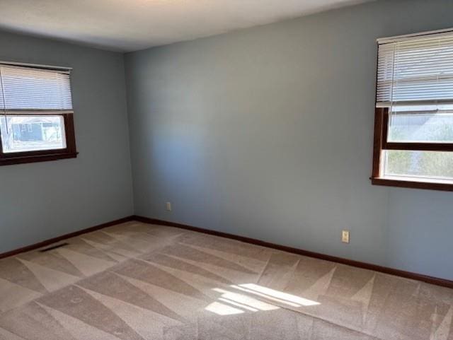 unfurnished room featuring visible vents, baseboards, and light carpet