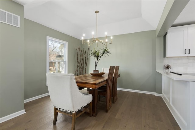 dining space with visible vents, baseboards, a notable chandelier, and dark wood finished floors