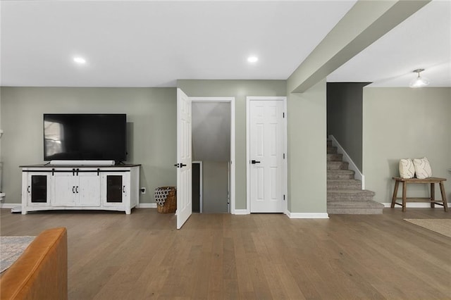 unfurnished living room featuring recessed lighting, stairs, baseboards, and wood finished floors