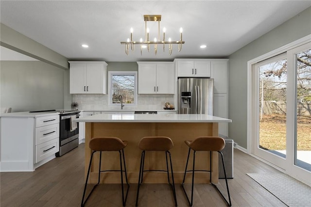 kitchen featuring a kitchen bar, tasteful backsplash, wood finished floors, a center island, and appliances with stainless steel finishes