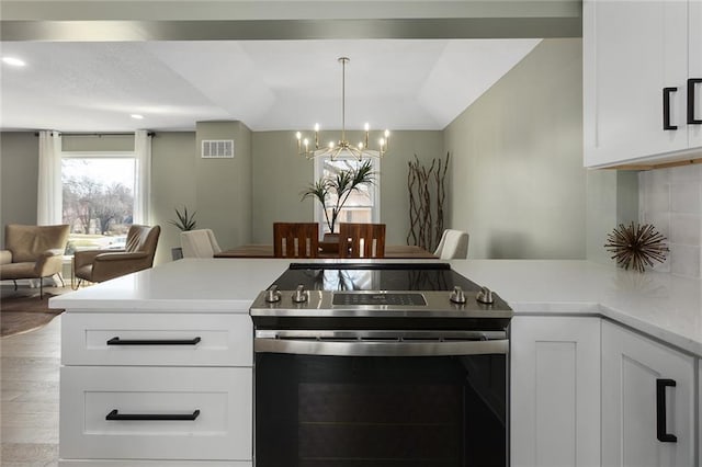 kitchen with tasteful backsplash, a chandelier, open floor plan, stainless steel range with electric cooktop, and white cabinets