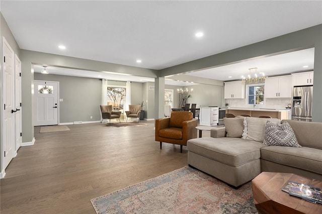 living area with recessed lighting, wood finished floors, baseboards, and a chandelier