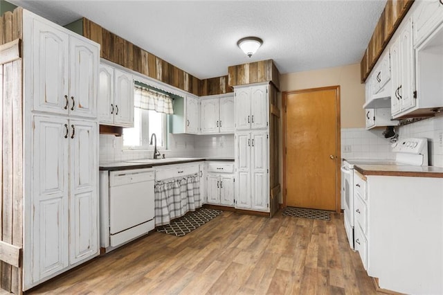 kitchen with white cabinets, white appliances, wood finished floors, and a sink