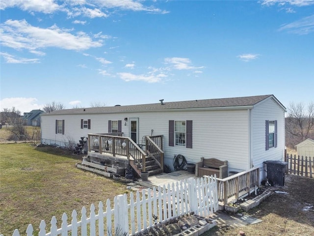 rear view of house featuring fence private yard, a deck, and a lawn