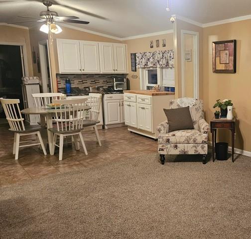 kitchen featuring backsplash, white cabinetry, ornamental molding, and ceiling fan