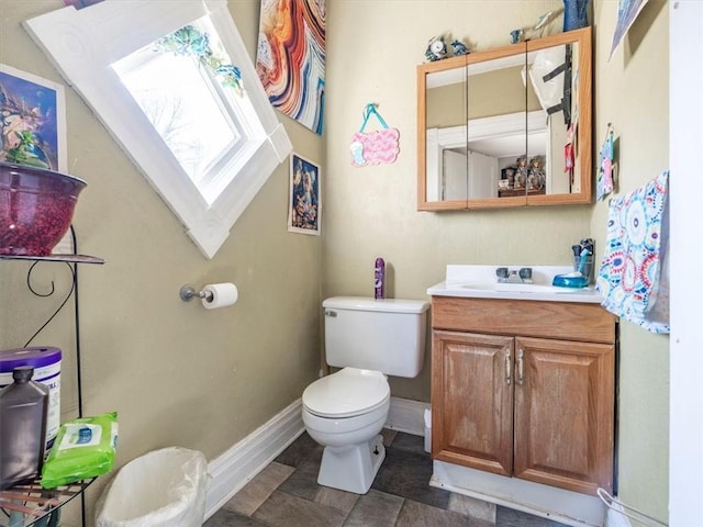 half bathroom featuring toilet, vanity, and baseboards