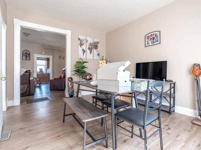 dining room with baseboards, visible vents, and light wood finished floors