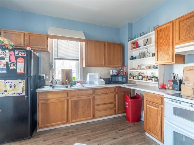 kitchen featuring wood finished floors, open shelves, black appliances, light countertops, and under cabinet range hood