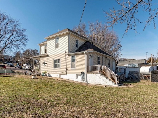 rear view of house with heating fuel, a yard, and fence