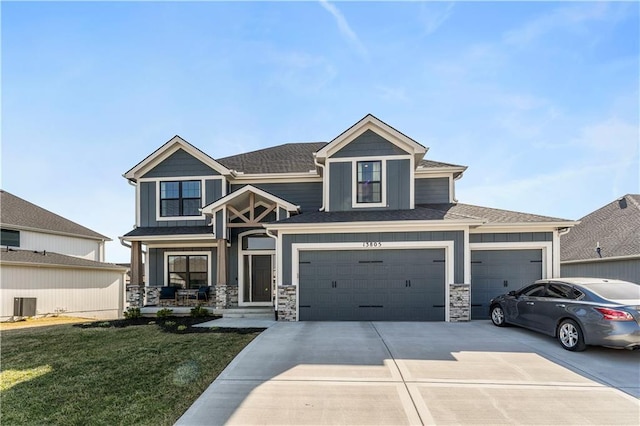 view of front of home featuring a front lawn, central AC unit, stone siding, and driveway