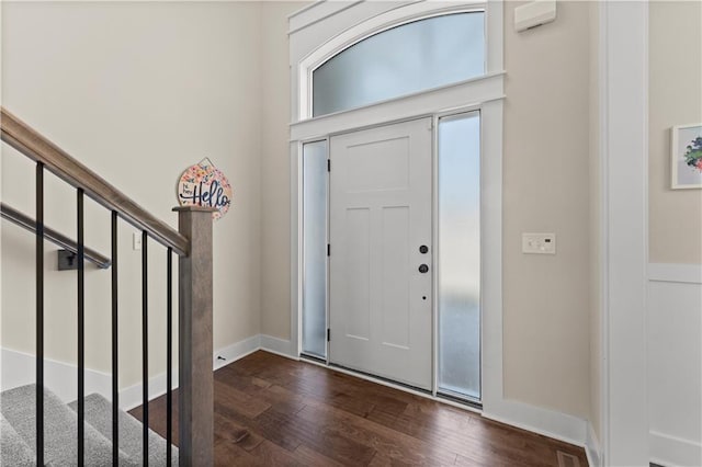 foyer entrance with dark wood-style floors, stairway, and baseboards