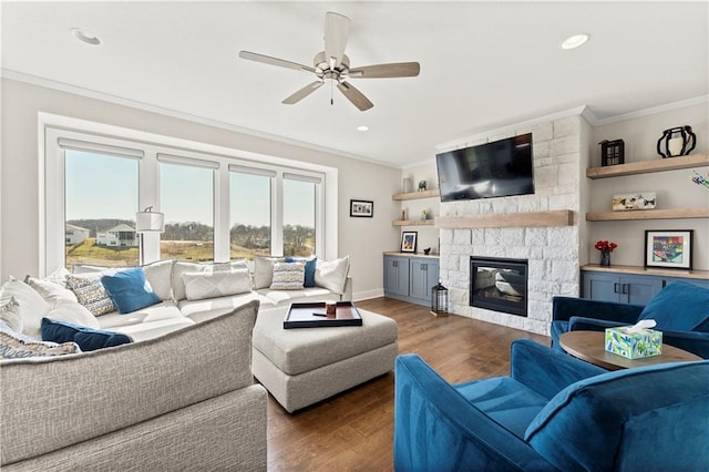 living area with ceiling fan, a fireplace, wood finished floors, and crown molding