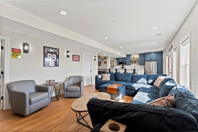 living room with recessed lighting, light wood-type flooring, and visible vents