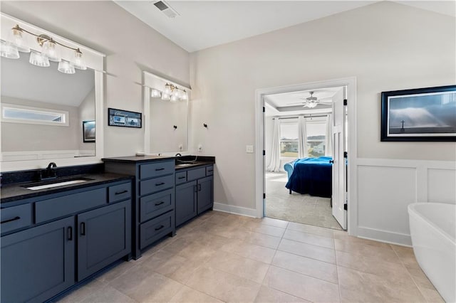 ensuite bathroom featuring double vanity, visible vents, a freestanding tub, and a sink