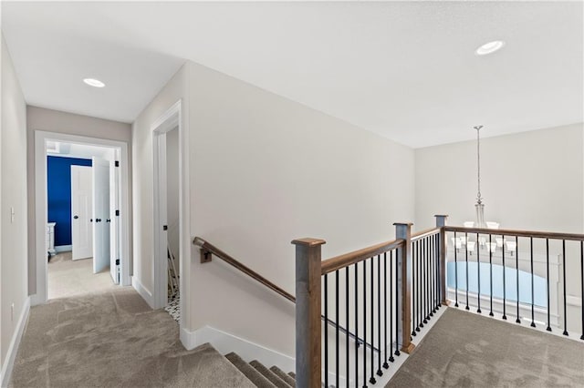 hallway featuring carpet, baseboards, recessed lighting, a notable chandelier, and an upstairs landing