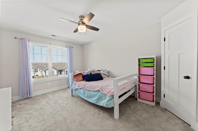 carpeted bedroom featuring visible vents, baseboards, a textured ceiling, and ceiling fan