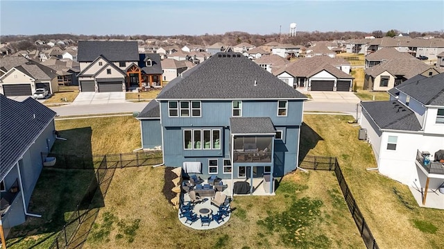 rear view of property featuring a patio, a fenced backyard, a yard, a residential view, and roof with shingles