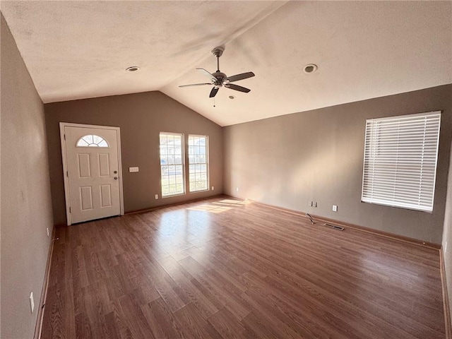 unfurnished living room with lofted ceiling, wood finished floors, baseboards, and ceiling fan