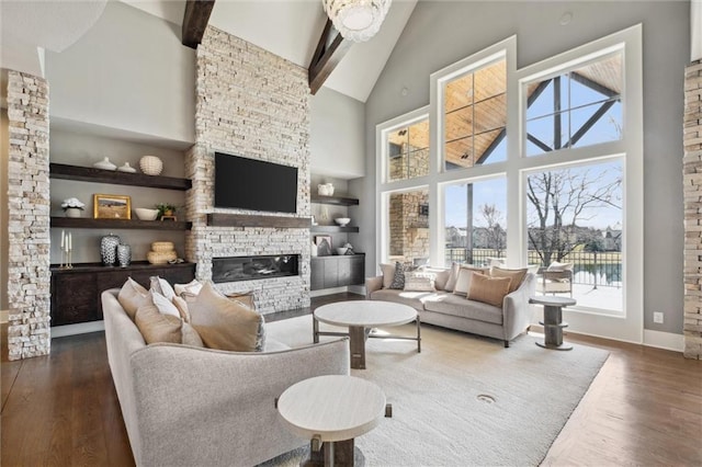 16121 Paradise St, Overland Park, KS 66221 - living room featuring high vaulted ceiling, a stone fireplace, wood finished floors, plenty of natural light, and beam ceiling