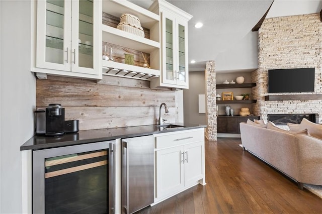 16121 Paradise St, Overland Park, KS 66221 - bar area with wine cooler, dark wood finished floors, a stone fireplace, and recessed lighting