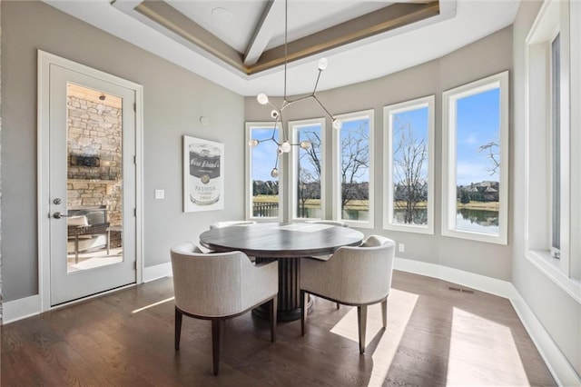 16121 Paradise St, Overland Park, KS 66221 - dining room with a tray ceiling, plenty of natural light, dark wood-style flooring, and a water view