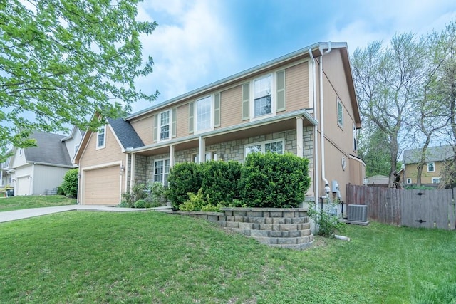 traditional-style home featuring a garage, central AC unit, fence, and a front yard