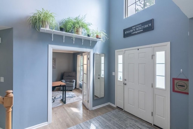 entrance foyer with baseboards, a high ceiling, and wood finished floors